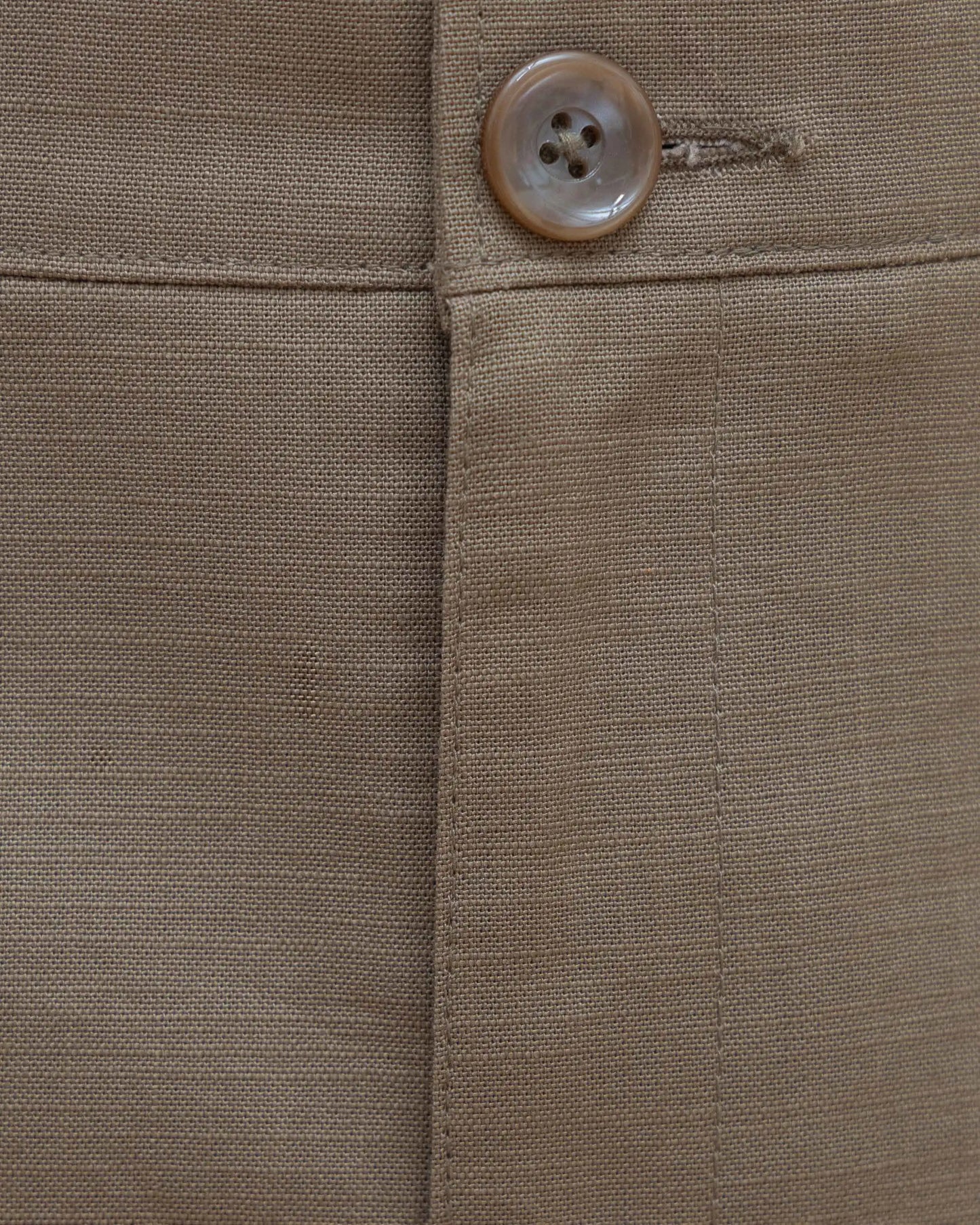 A close-up of a button on NAD olive green cotton pants for men.