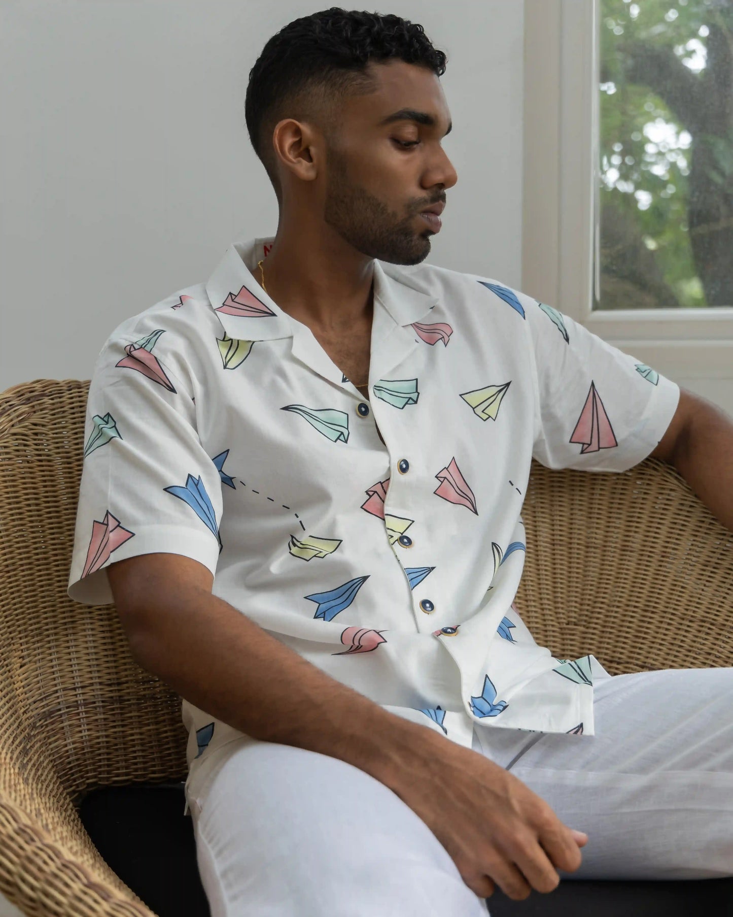 A model seated, showcasing NAD's paper planes shirt for men.