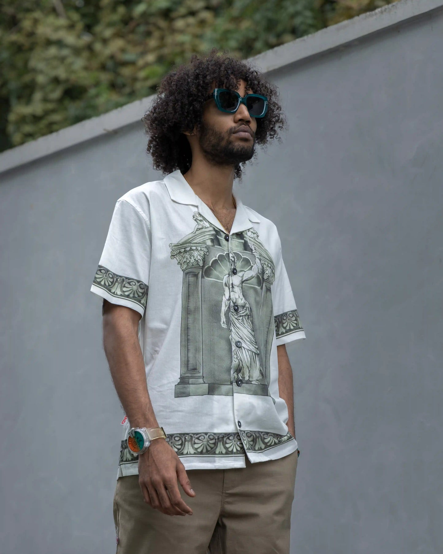 Model wearing NAD's Zeus print shirt paired with brown pants and sunglasses.