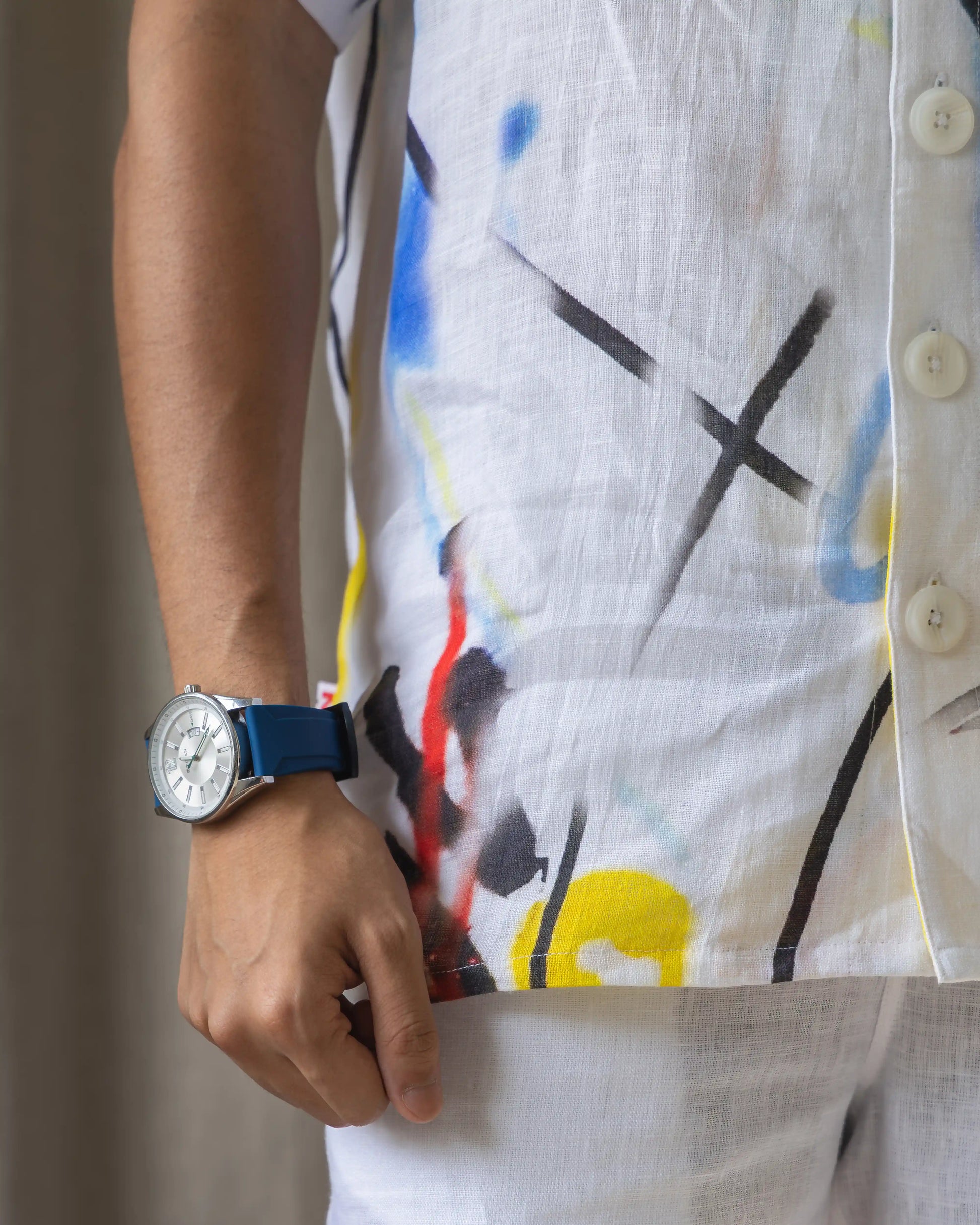 A man dressed in NAD's white abstract shirt for men, accessorised with a blue watch on his wrist. 