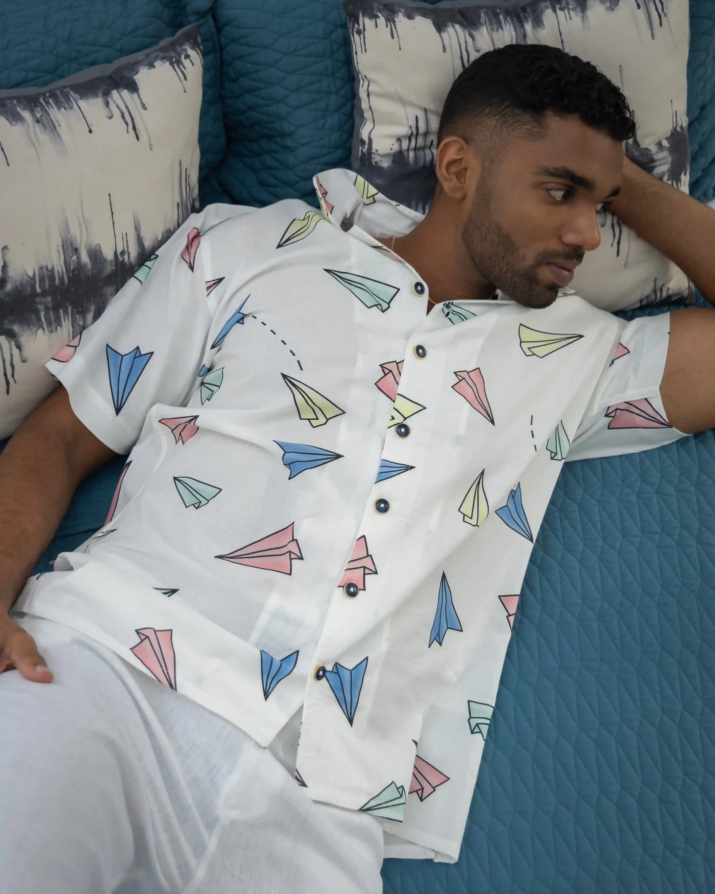 Model relaxing in NAD's paper plane print shirt for men.