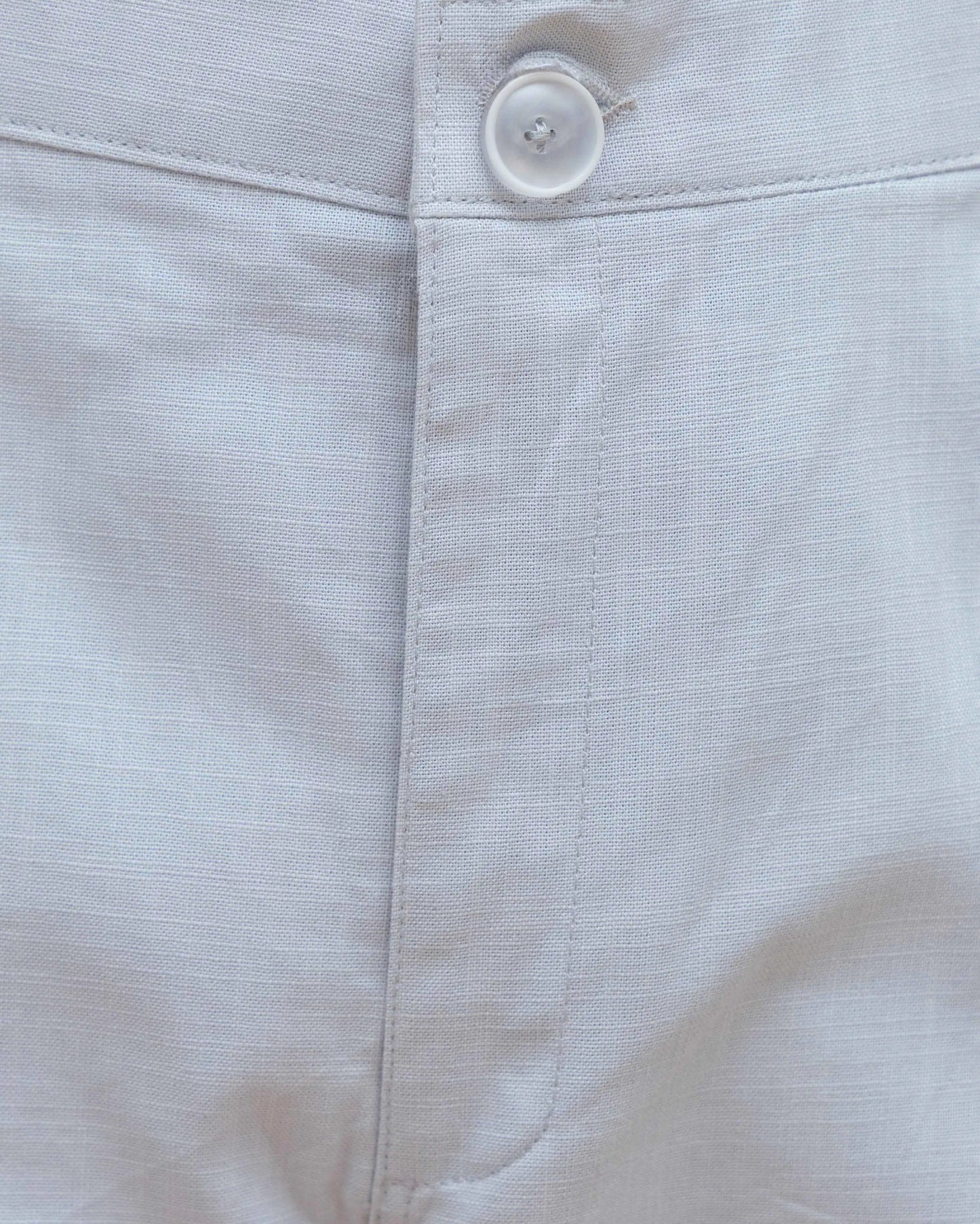 Close-up of a button and a zipper on white pants for men.