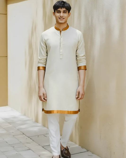 Man wearing a cream kurta with gold accents against a neutral background