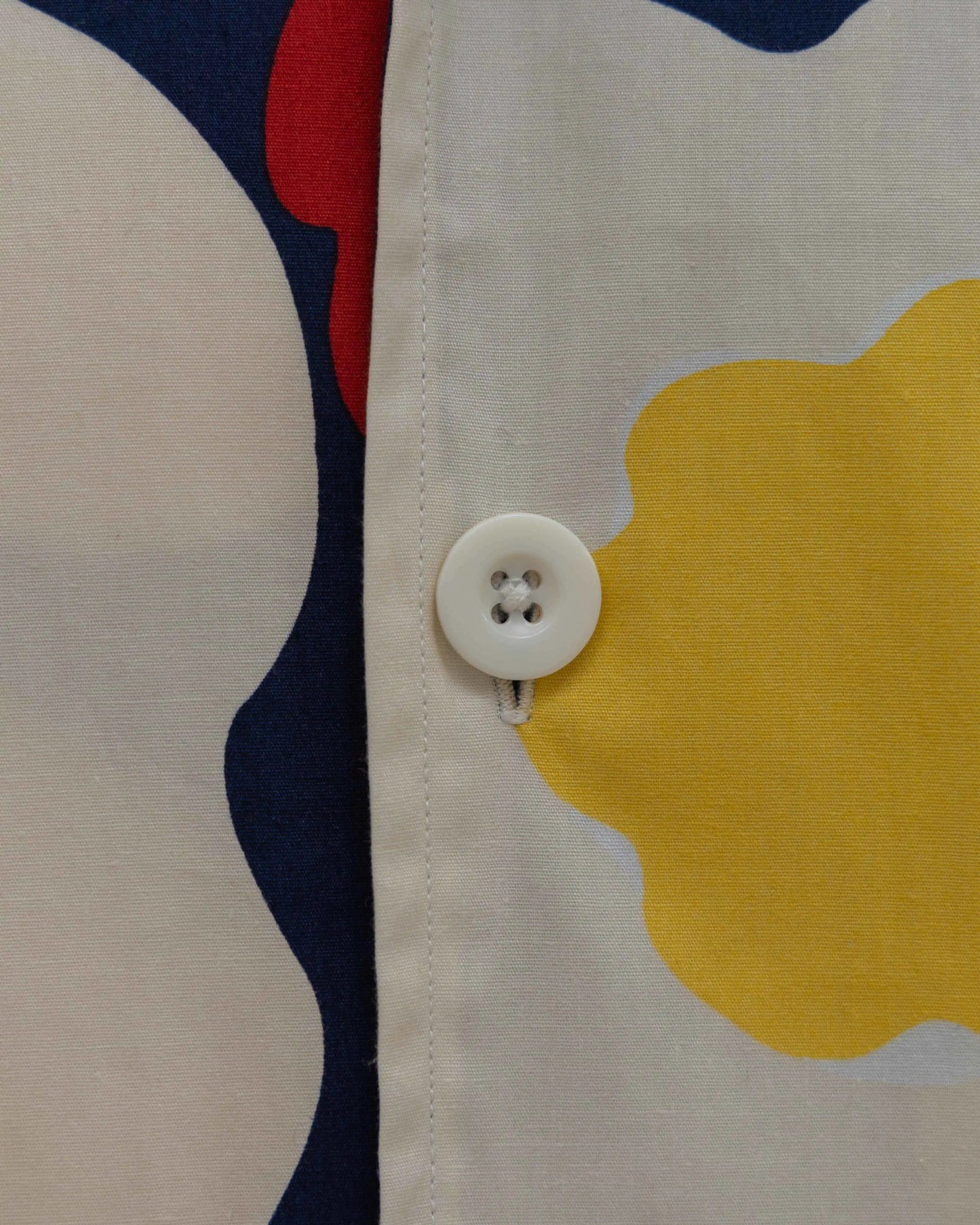 Close-up of a button on a yellow floral poplin shirt for men by NAD